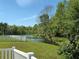 Scenic backyard view overlooking a serene lake surrounded by lush greenery and a white picket fence at 1227 Big Creek Dr, Wesley Chapel, FL 33544