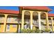 Attractive condo building featuring red roof, yellow walls, white stairs, and manicured landscaping at 1301 S Hercules Ave # 3, Clearwater, FL 33764