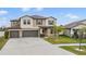 A two story home features a three car garage, manicured lawn and inviting front door at 13549 Willow Bluestar Loop, Riverview, FL 33579