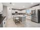 Well-lit kitchen with white cabinets, a central island with barstool seating, and stainless steel appliances at 13549 Willow Bluestar Loop, Riverview, FL 33579