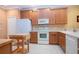 Functional kitchen featuring white appliances, wood cabinets, and tiled backsplash at 221 Shell Falls Dr, Apollo Beach, FL 33572