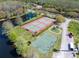 A high-angle shot of tennis and basketball courts, a playground, and a lake within a residential neighborhood at 3639 Darston St, Palm Harbor, FL 34685