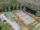 A high-angle shot of tennis and basketball courts, a playground, and a lake within a residential neighborhood at 3639 Darston St, Palm Harbor, FL 34685
