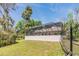 View of screened-in pool enclosure and lush yard for outdoor activities and relaxation at 401 Apache Trl, Brandon, FL 33511