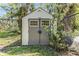 Backyard shed features double doors, windows, and neutral tones, enclosed within a chain link fence at 401 Apache Trl, Brandon, FL 33511