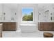 Bright bathroom with dual vanities, soaking tub beneath a window, and marble flooring, offering a spa-like experience at 4614 W Lowell Ave, Tampa, FL 33629