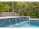 The luxurious pool has a serene water feature and is surrounded by lush tropical landscaping at 4614 W Lowell Ave, Tampa, FL 33629