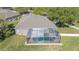 Aerial view of the property showcasing a backyard pool, lush green grass, and mature trees at 5404 Garden Arbor Dr, Lutz, FL 33558