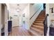 Inviting foyer with hardwood flooring, a staircase, white front door, and views into the dining area at 64 Pelican Pl, Belleair, FL 33756