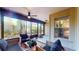 Enclosed porch with comfortable seating, ceiling fan, and serene views of the backyard at 64 Pelican Pl, Belleair, FL 33756