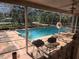 Relaxing screened-in patio with pool view, featuring a barbecue area and refreshing blue water at 6473 Blackbird Ave, Weeki Wachee, FL 34613