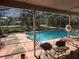 Relaxing screened-in patio with pool view, featuring a barbecue area and refreshing blue water at 6473 Blackbird Ave, Weeki Wachee, FL 34613