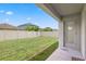 View of the grass backyard with a covered patio, privacy fence, and exterior door at 7233 Lumber Port Dr, Ruskin, FL 33573