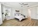 Airy bedroom featuring wood floors, tray ceiling, shutters, and neutral decor at 8766 Shadyside Ln, Land O Lakes, FL 34637