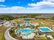 An aerial view of a community pool area with a splash pad, pool, and ample lounging space, surrounded by lush greenery at 8766 Shadyside Ln, Land O Lakes, FL 34637