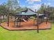 Inviting neighborhood playground covered by a sunshade, offering fun and exercise for children on soft mulch at 8766 Shadyside Ln, Land O Lakes, FL 34637