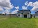 Grassy backyard featuring a well-maintained lawn and a charming two-story home under a bright blue sky with fluffy clouds at 10821 Windswept Garden Way, Tampa, FL 33647