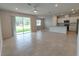 Open-concept living room featuring tile floors, sliding glass doors, and a view into the modern kitchen at 10821 Windswept Garden Way, Tampa, FL 33647