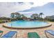 A community pool area with lounge chairs for relaxing near the water, and tall trees in the background at 11436 2Nd N St # 4, St Petersburg, FL 33716