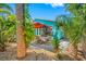 Charming backyard with outdoor seating area, palm trees, and a bright teal house, ideal for relaxation at 119 13Th Ave, Indian Rocks Beach, FL 33785