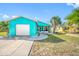 Bright teal house with well-manicured lawn, stone walkway, and a garage is perfect for coastal living at 119 13Th Ave, Indian Rocks Beach, FL 33785
