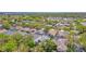 Aerial view showcases a neighborhood with mature trees, manicured lawns, swimming pools, and a glimpse of the lake in the distance at 1210 Paradise Lake Dr, Tarpon Springs, FL 34689
