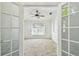 Bright bedroom with neutral carpet, a ceiling fan, and double doors at 1210 Paradise Lake Dr, Tarpon Springs, FL 34689
