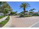 A gated community entrance features lush landscaping, palm trees, and a brick-paved circular driveway at 1210 Paradise Lake Dr, Tarpon Springs, FL 34689