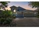 Charming single-Gathering home with a three-car garage and a well-manicured lawn at dusk at 1210 Paradise Lake Dr, Tarpon Springs, FL 34689
