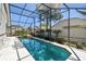 An oversized pool with a hot tub features a covered screen and tropical landscaping at 1210 Paradise Lake Dr, Tarpon Springs, FL 34689