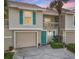 Charming two-story townhome featuring a one-car garage, a quaint balcony, and a vibrant turquoise front door at 12204 Sun Vista W Ct, Treasure Island, FL 33706