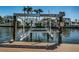 Dock with a mechanical boat lift overlooking calm water and waterfront homes at 1233 Eden Isle Ne Dr, St Petersburg, FL 33704