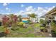 Scenic backyard with vibrant plants, cozy swing, mature palm trees, and well-maintained lawn, ideal for relaxation at 14407 Alistar Manor Dr, Wimauma, FL 33598