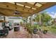 Inviting covered patio featuring comfortable seating, ceiling fan, outdoor kitchen, and a view of the lush backyard at 14407 Alistar Manor Dr, Wimauma, FL 33598
