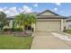 Charming single-story home featuring a well-manicured lawn, mature landscaping, and a two-car garage at 14407 Alistar Manor Dr, Wimauma, FL 33598