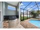A screened-in lanai with a built in grill and view of the pool and backyard at 18413 Eastwyck Dr, Tampa, FL 33647