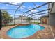 A large screened-in pool with brick pavers and an attached spa tub at 18413 Eastwyck Dr, Tampa, FL 33647