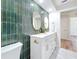 Contemporary bathroom with a double vanity, sleek green tiling, gold hardware, and a glimpse of wood flooring at 1991 67Th S Ave, St Petersburg, FL 33712