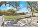 Backyard featuring a paved patio, white picket fences, and mature trees providing shade and privacy at 2124 Crowsnest Dr, Palm Harbor, FL 34685