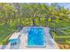 Community pool surrounded by mature trees, green spaces, and a fenced area with lounge chairs at 2124 Crowsnest Dr, Palm Harbor, FL 34685