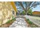 A tidy side yard featuring a paver pathway, neat landscaping, and a charming white picket fence at 2124 Crowsnest Dr, Palm Harbor, FL 34685
