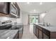 An open kitchen with stainless steel appliances, dark cabinets, and granite countertops overlooking the living area at 2892 Beluga Bay Dr, Odessa, FL 33556