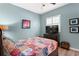 Comfortable bedroom with a colorful quilt, wooden floors, and blue walls at 3003 Magdalene Woods Dr, Tampa, FL 33618