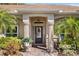 Elegant front entrance with decorative columns, a glass-accented door, and lush tropical plants at 3003 Magdalene Woods Dr, Tampa, FL 33618