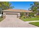 Beautifully landscaped front exterior with a brick driveway and a two-car garage at 3003 Magdalene Woods Dr, Tampa, FL 33618