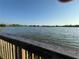 Picturesque water view from a wooden railing, showcasing a calm lake and distant treeline under a clear sky at 3212 W Hartnett Ave, Tampa, FL 33611