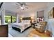 Light-filled bedroom featuring a ceiling fan, hardwood floors, and view of the landscaped yard at 329 Laurel Falls Dr, Apollo Beach, FL 33572