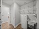 Laundry room featuring wood-look floors, a utility sink, mini-fridge and convenient wire shelving at 34411 Sahalee Loop, Dade City, FL 33525