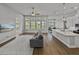 Bright living room with wood floors, a ceiling fan, and large windows offering natural light at 34411 Sahalee Loop, Dade City, FL 33525