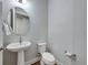Cozy powder room with a pedestal sink, toilet, and round mirror at 34411 Sahalee Loop, Dade City, FL 33525